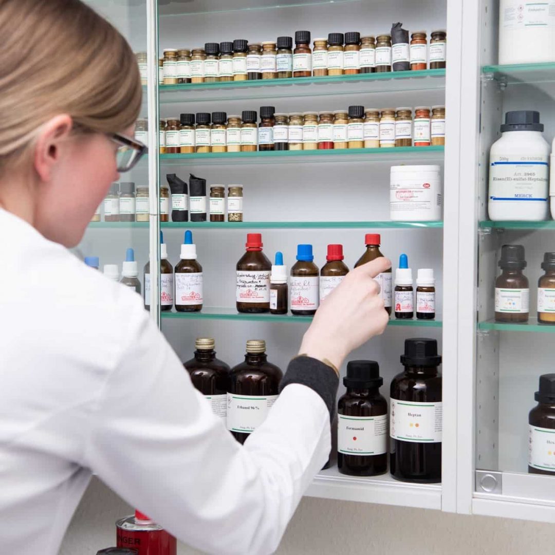 Apothekerin sortiert medizinische Flaschen im Schrank.